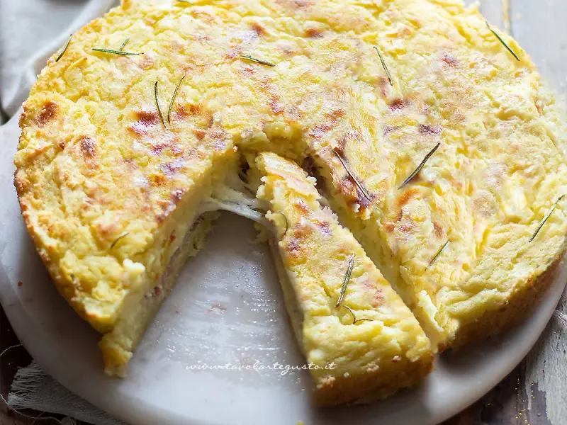 Una fetta di torta di patate filante, dorata e profumata al rosmarino, pronta per essere gustata.