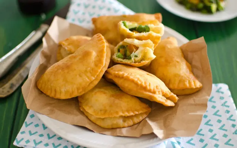 Panzerotti al forno dorati e ripieni di verdure, serviti su carta da forno.