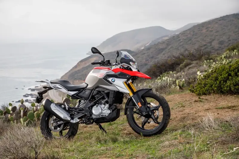 BMW G 310 GS na tle górskiego krajobrazu z widokiem na ocean. Poznaj jego dane techniczne i możliwości terenowe.