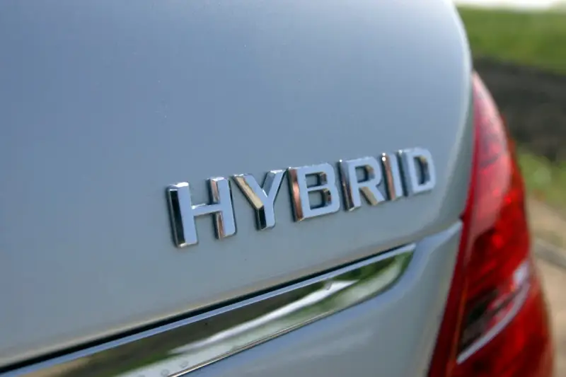 Chromowane napisy "HYBRID" na białym nadwoziu samochodu. To nowoczesny hybrydowy pojazd elektryczny, gotowy na ekologiczną podróż.