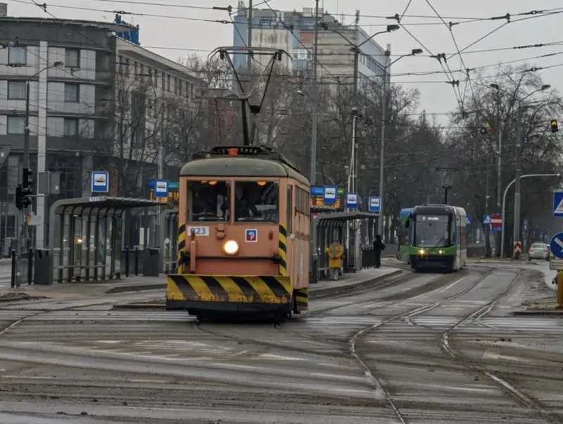 Gdy pada w Szczecinie, można wsiąść do tramwaju i podziwiać miasto z okna. Dwa tramwaje na torach, jeden pomarańczowy, drugi zielony.