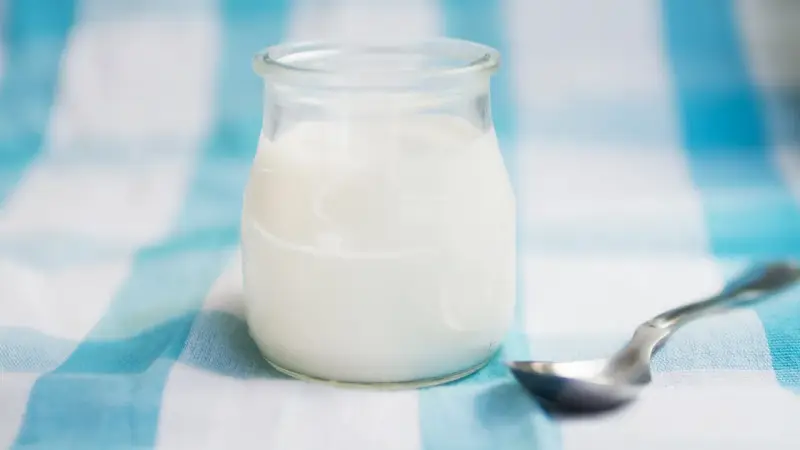 Słoiczek z domowym jogurtem, pełnym naturalnych probiotyków, czeka na łyżeczkę.