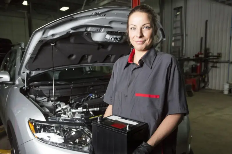 Meccanica sorridente con una nuova batteria, pronta per mostrare come montare una batteria auto.