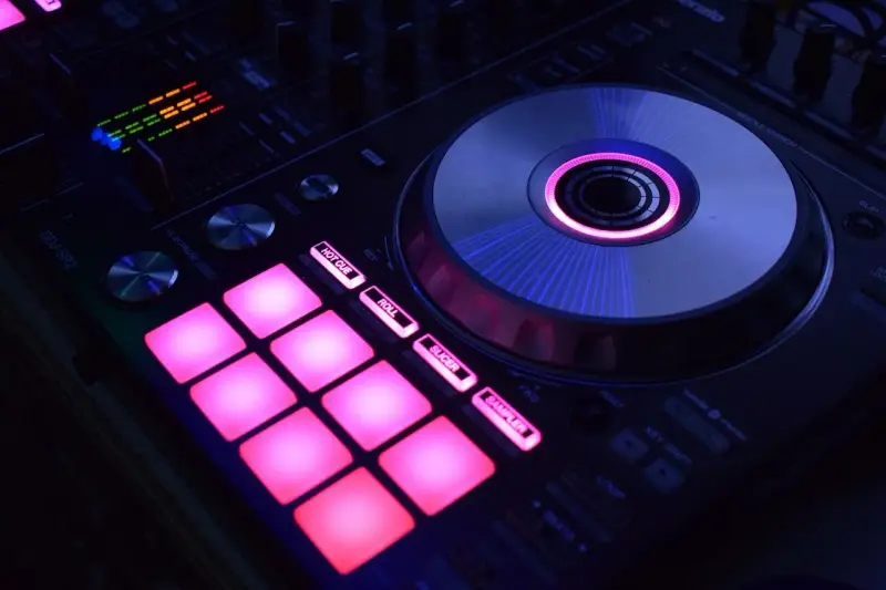 DJ kontroler z podświetlanymi na różowo padami i świecącym na niebiesko talerzem. Idealny do tworzenia muzyki, np. dubstep co to za gatunek?