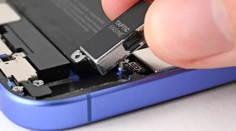 Dłoń wyjmuje moduł Taptic Engine z wnętrza telefonu, element odpowiedzialny za zaawansowane wibracje i 3D Touch.
