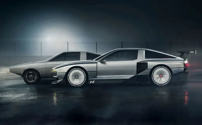 Dwa samochody Hyundai N Vision 74 stoją obok siebie na mokrej nawierzchni. Jeden jest bardziej klasyczny, drugi futurystyczny.