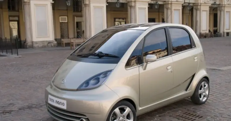 Złoty Tata Nano na brukowanym placu przed zabytkową kamienicą.