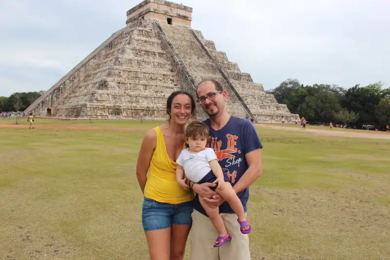 Famiglia felice in vacanza in Messico con bambini, davanti alla piramide di Chichen Itza.