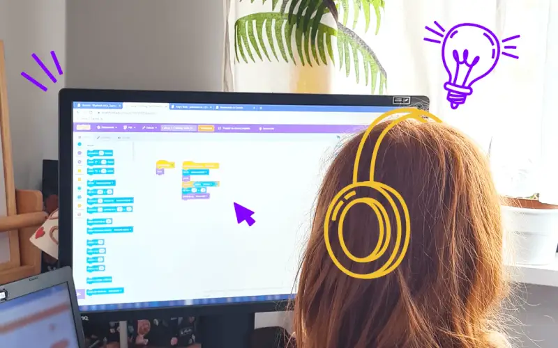 Dziewczynka w słuchawkach tworzy kod w Scratch po polsku, ucząc się programowania.