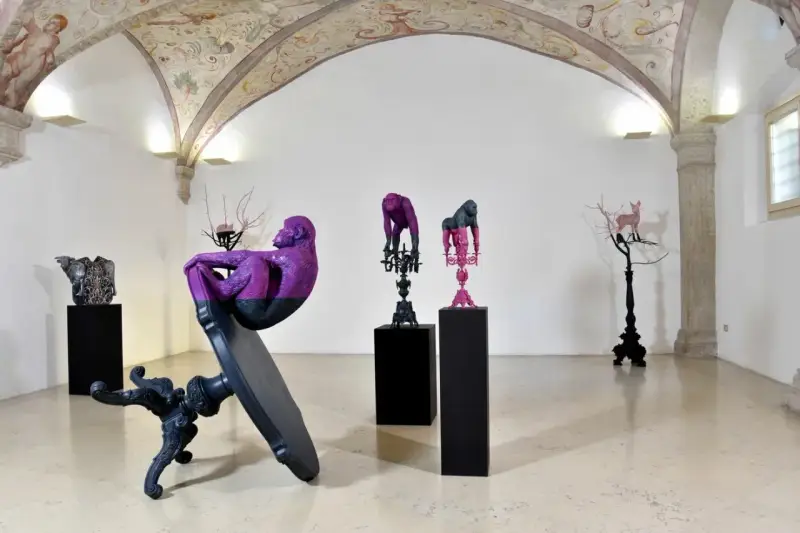Sculture di scimmie e cervi colorati, opere di **artisti contemporanei famosi**, in una galleria con affreschi sul soffitto.