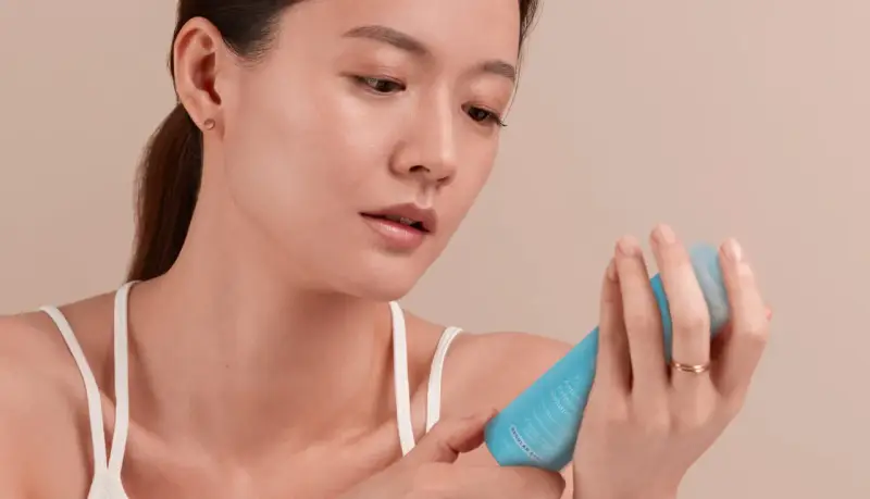 Une femme examine un tube de crème visage périmée, pas encore ouverte.