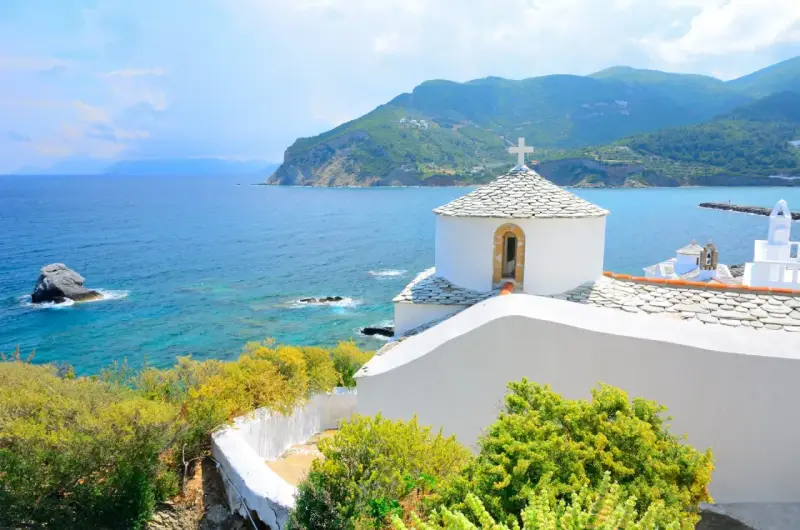 Malownicza zatoka i białe kościółki na wzgórzu. Idealne miejsce na skopelos wakacje.