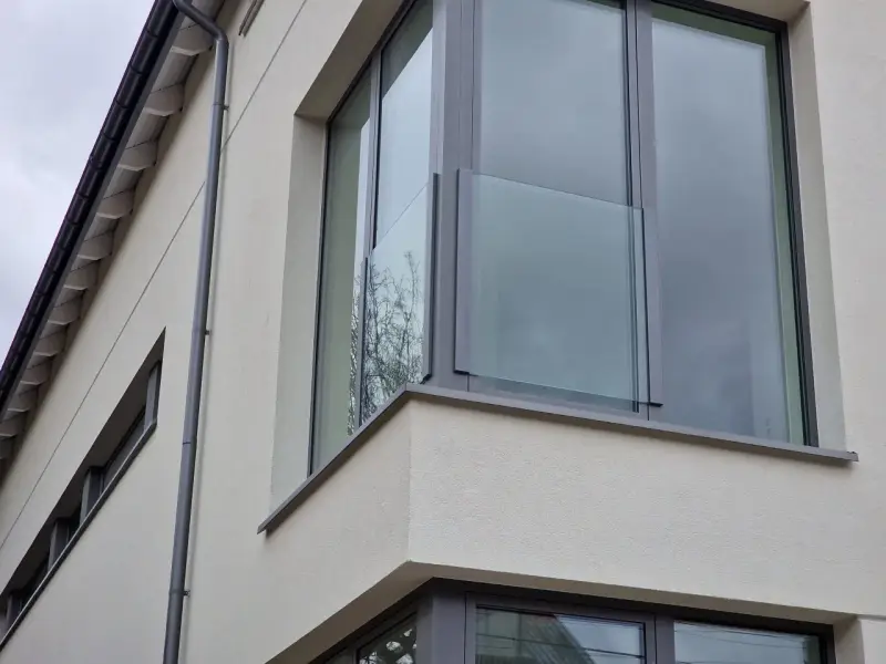 Nowoczesne portfenetry z przeszklonymi balustradami na jasnej elewacji.