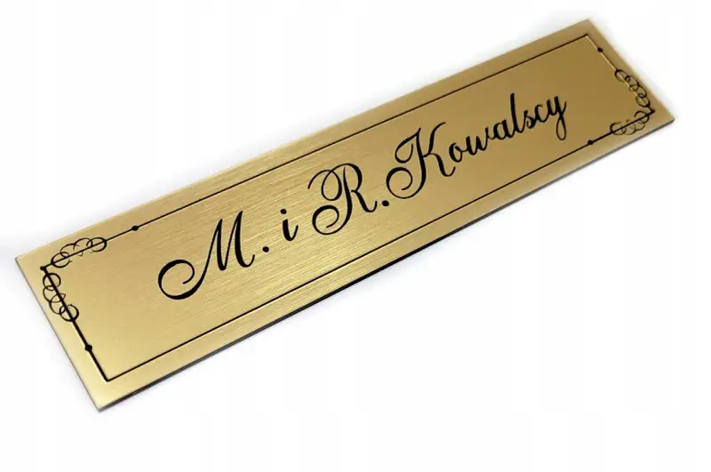 Elegancki, złoty szyld z napisem "M. i R. Kowalscy" w ozdobnej ramce.