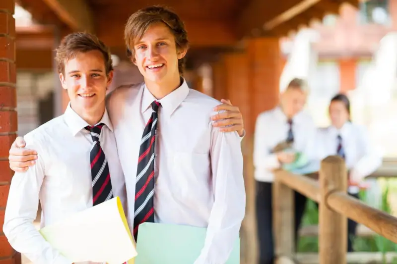 Deux adolescents souriants, portant des chemises blanches et des cravates, profitent de leurs vacances scolaires en Irlande.