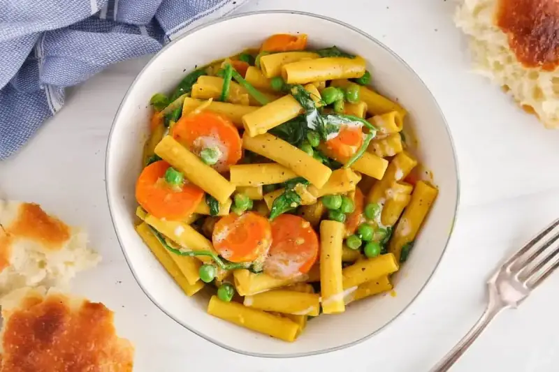Makaron z mlekiem kokosowym i curry, z marchewką i groszkiem. Kremowy sos otula złociste rurki, tworząc aromatyczne danie.