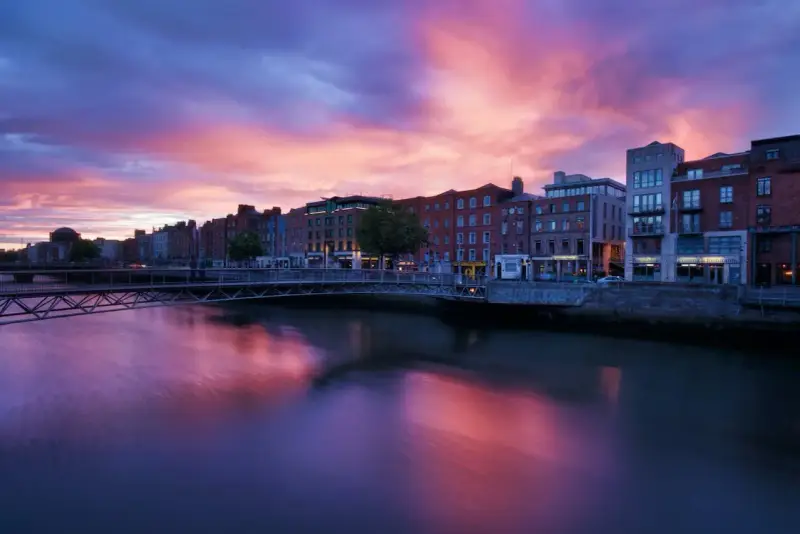 Zachód słońca nad rzeką Liffey w Dublinie. Widok na most i zabytkowe kamienice, idealne miejsce, by zobaczyć Dublin.