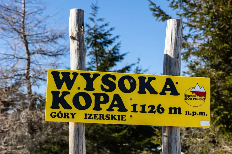 Żółta tablica informuje o szczycie Wysoka Kopa, najwyższym szczycie Gór Izerskich, na wysokości 1126 m n.p.m.