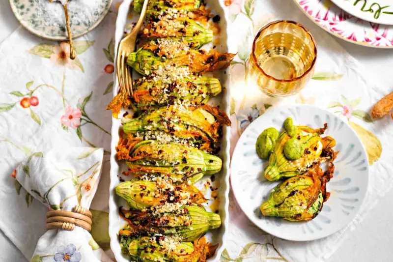 Deliziosi fiori di zucca al forno, ripieni e dorati, serviti su un piatto con un tocco di verde.