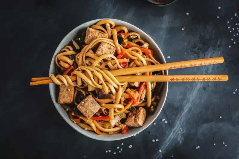 Miseczka z makaronem udon, tofu i warzywami, gotowa do podania. Idealny przepis na pad udon.