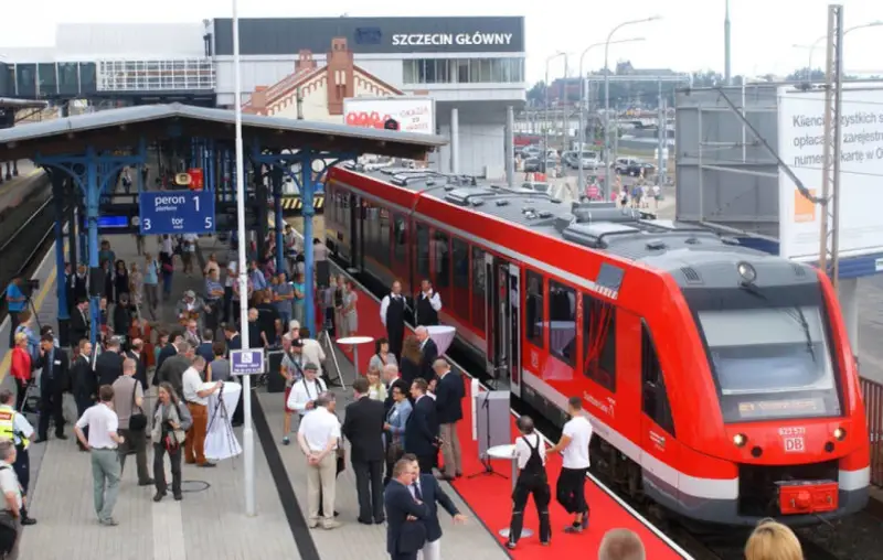 Czerwony pociąg na peronie dworca Szczecin Główny, gotowy do podróży do Berlina. Ludzie czekają na platformie.