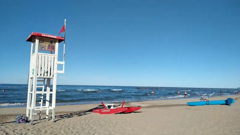 Torre di salvataggio e barchini sulla spiaggia di Rimini, pronti per nuove storie di mare.