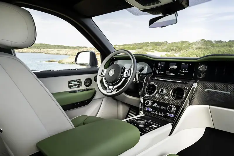 Wnętrze luksusowego Rolls-Royce SUV z zielonymi i białymi skórzanymi detalami, widok na morze.