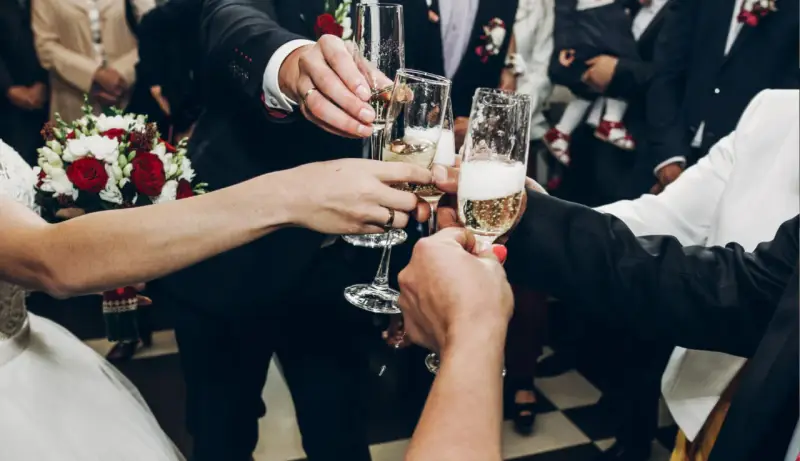 Wznoszenie toastu szampanem na weselu. Pytanie "ile wina na wesele" jest kluczowe, by wszyscy mogli się cieszyć.