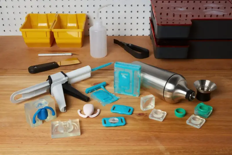 Attrezzi per la lavorazione della resina, inclusi stampi in silicone, pistola per colla e contenitori, utili per capire come pulire gli stampi in silicone dalla resina.