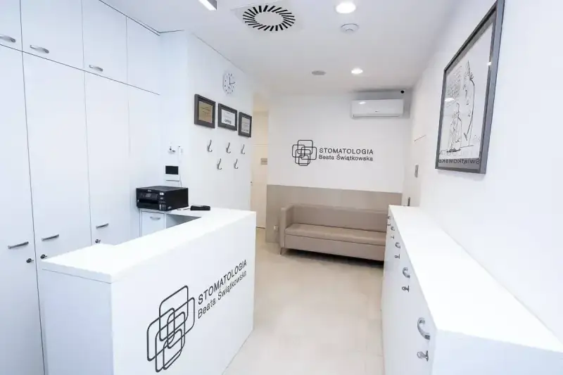 Nowoczesne wnętrze recepcji gabinetu stomatologicznego z kanapą i logotypem.