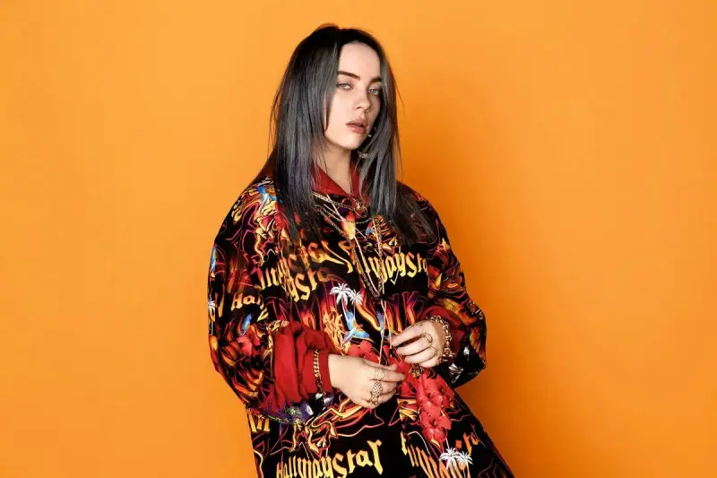 Billie Eilish w kolorowej bluzie, z mnóstwem złotych łańcuchów i pierścionków, jakby przygotowywała się do odebrania kolejnych nagród.
