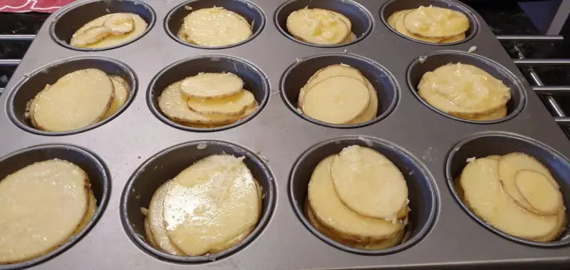Tunna skivor av potatis i muffinsform, redo att bakas. Enkel och god rätt.