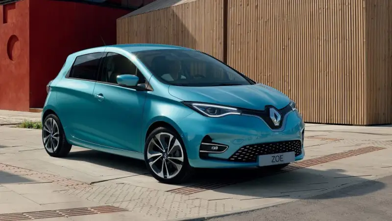 Błękitny Renault Zoe z nowoczesnymi światłami LED stoi na tle drewnianej elewacji.