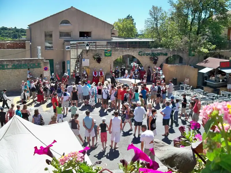 Foule en costume d'époque lors de la fête de la veraison, avec des musiciens et des stands.