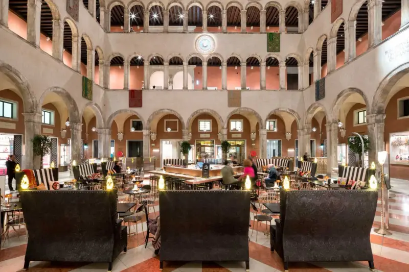 Lussuoso cortile interno con arcate, ideale per scoprire dove fare shopping a Venezia, tra negozi eleganti e aree lounge.