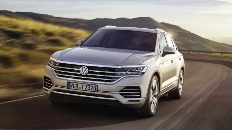 Elegancki Volkswagen Touareg, jeden z wielu imponujących volkswagen modele, pędzi po krętej drodze wśród wzgórz.