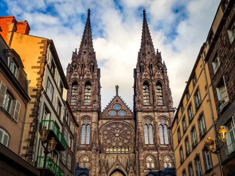 La cathédrale de Clermont-Ferrand, une des plus belles cathédrales de France, se dresse fièrement entre des immeubles anciens.