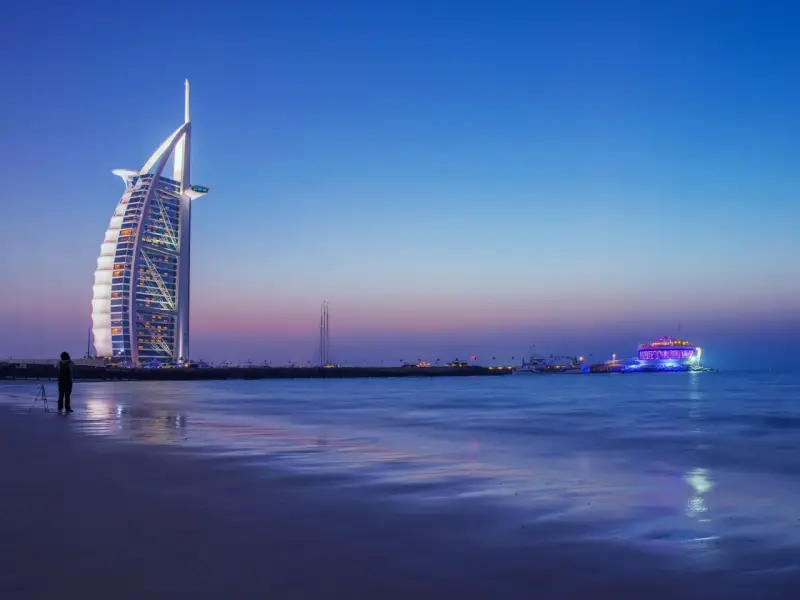 Wieżowiec Burdż al-Arab i plaża w Dubaju o zmierzchu.