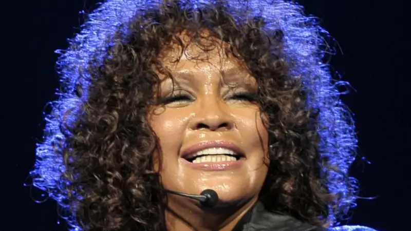 Whitney Houston z zamkniętymi oczami, w pełni emocji, pokazuje niesamowitą **skalę głosu**.