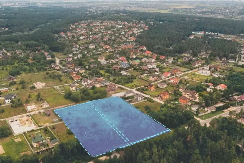 Działki bez planu ogólnego gminy będą niesprzedawalne od lipca 2026. Aerial view of suburban housing development with a highlighted plot of land.