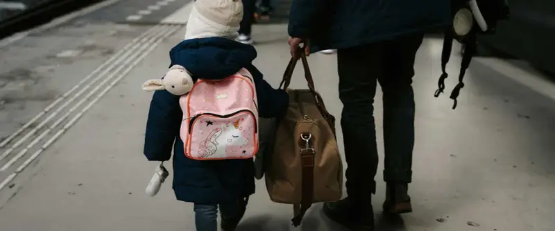 Enfant avec sac à dos licorne et doudou, accompagnant un adulte. Voyage pour une autorisation de sortie de territoire mineur parents séparés.