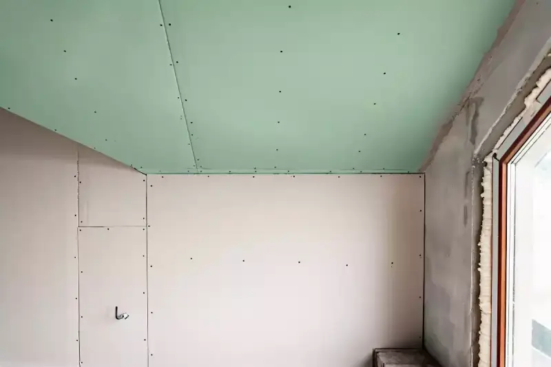 Jonction mur plafond placo, avec un plafond vert et des murs blancs. Travaux de rénovation en cours.