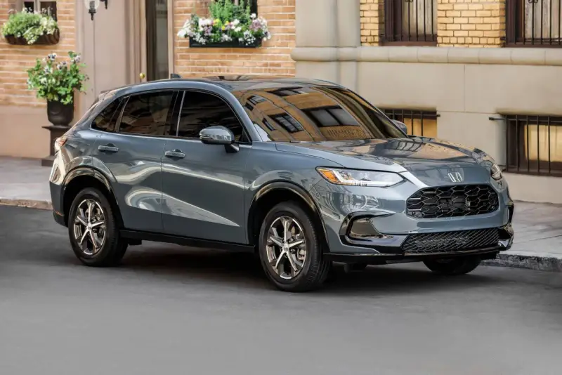 Elegancki, szary SUV Honda HR-V stoi na ulicy przed budynkiem z cegły.