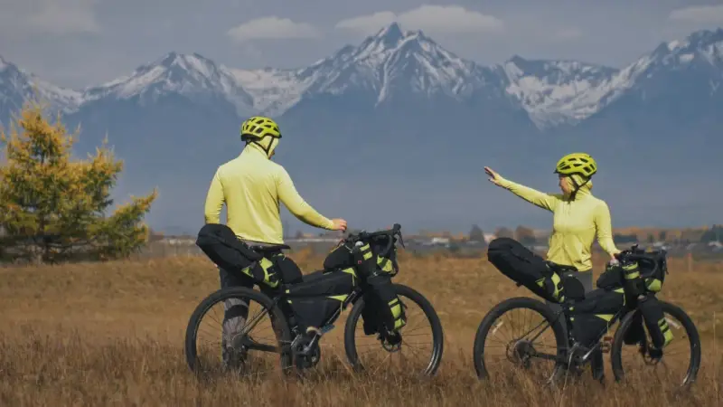 Para szykuje się na przygodę bike packing. W tle majestatyczne, ośnieżone góry.