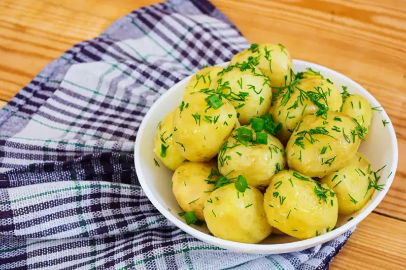 Młode ziemniaki w misce, posypane koperkiem i szczypiorkiem. Idealne na lato, a ile gotować młode ziemniaki? Krótko!