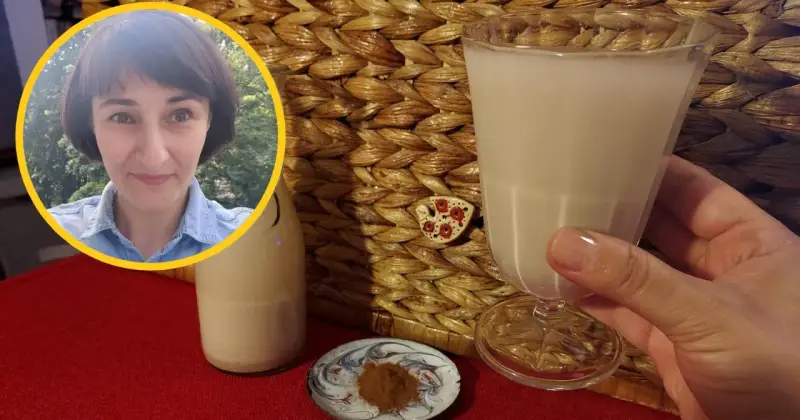 Kobieta z uśmiechem prezentuje szklankę z wodą owsianą, obok butelka i cynamon.