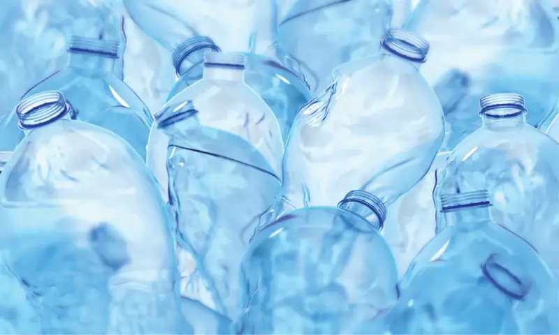 Mnóstwo pustych, niebieskich butelek po wodzie, niektóre z zakrętkami, inne bez. Tworzą one chaotyczny, ale estetyczny **dinp**.