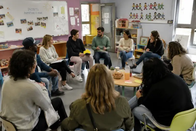 Des participants échangent lors d'une formation, peut-être des stages BAFA, dans une salle colorée.