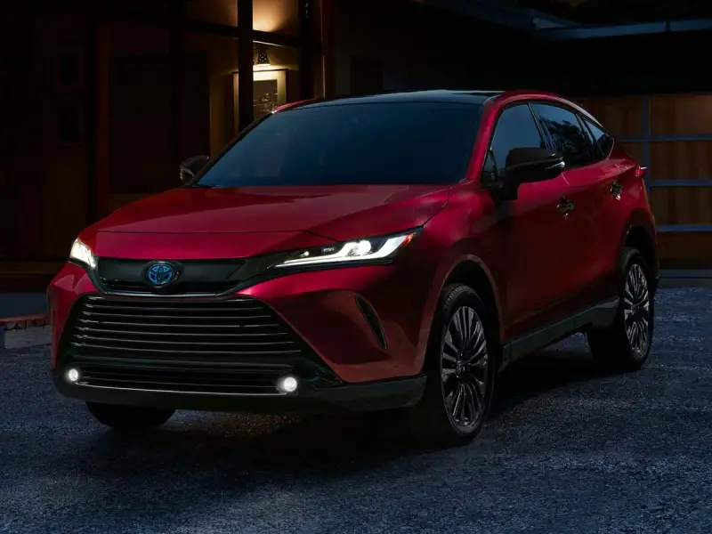 Elegancka, czerwona Toyota Venza z nowoczesnymi światłami LED stoi przed domem o zmierzchu.