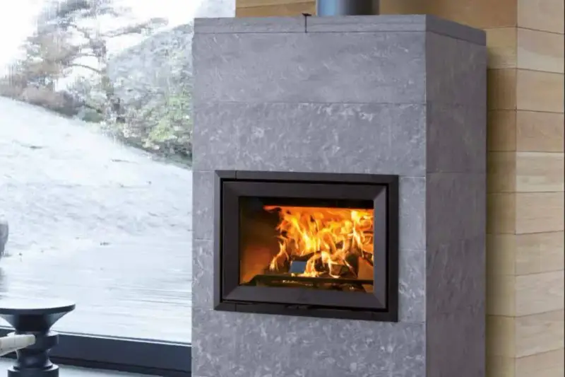 Chimenea moderna de piedra gris con fuego crepitante. Es hora de insertarleña para mantener el calor.